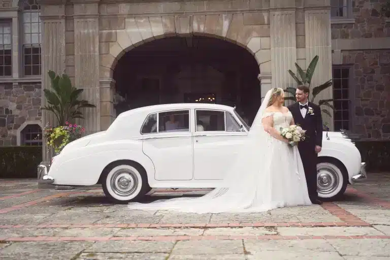 Bride and groom outdoors near the car at the wedding venue 768x512