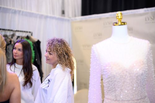 Canada's Bridal Show October 2026 - Exhibitors chatting beside a beaded gown at the LVSH booth
